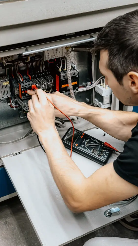 Électricien contrôlant un tableau électrique au multimètre