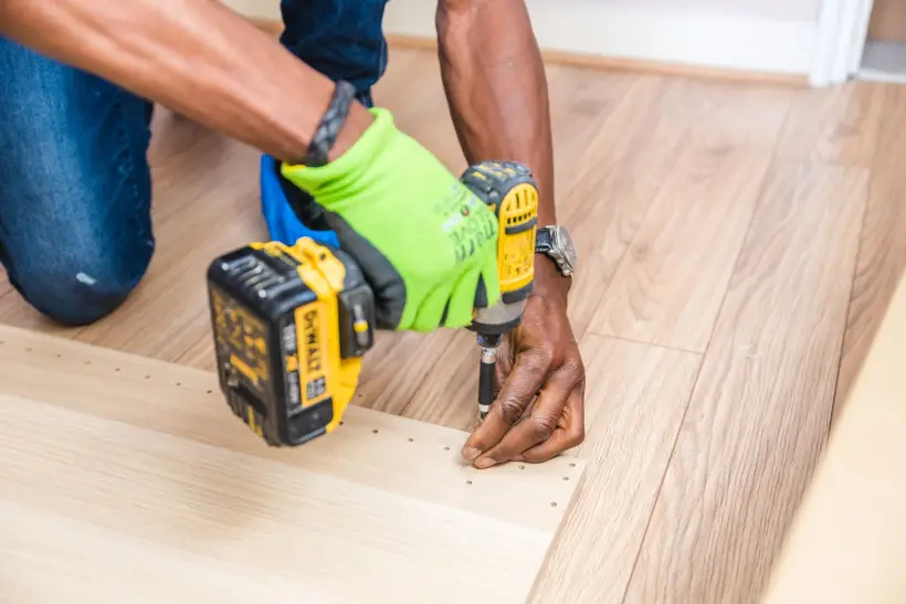 Artisan utilisant une visseuse pour de petits travaux dans une maison