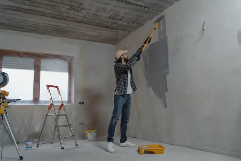 Peintre appliquant une peinture au rouleau sur un mur intérieur