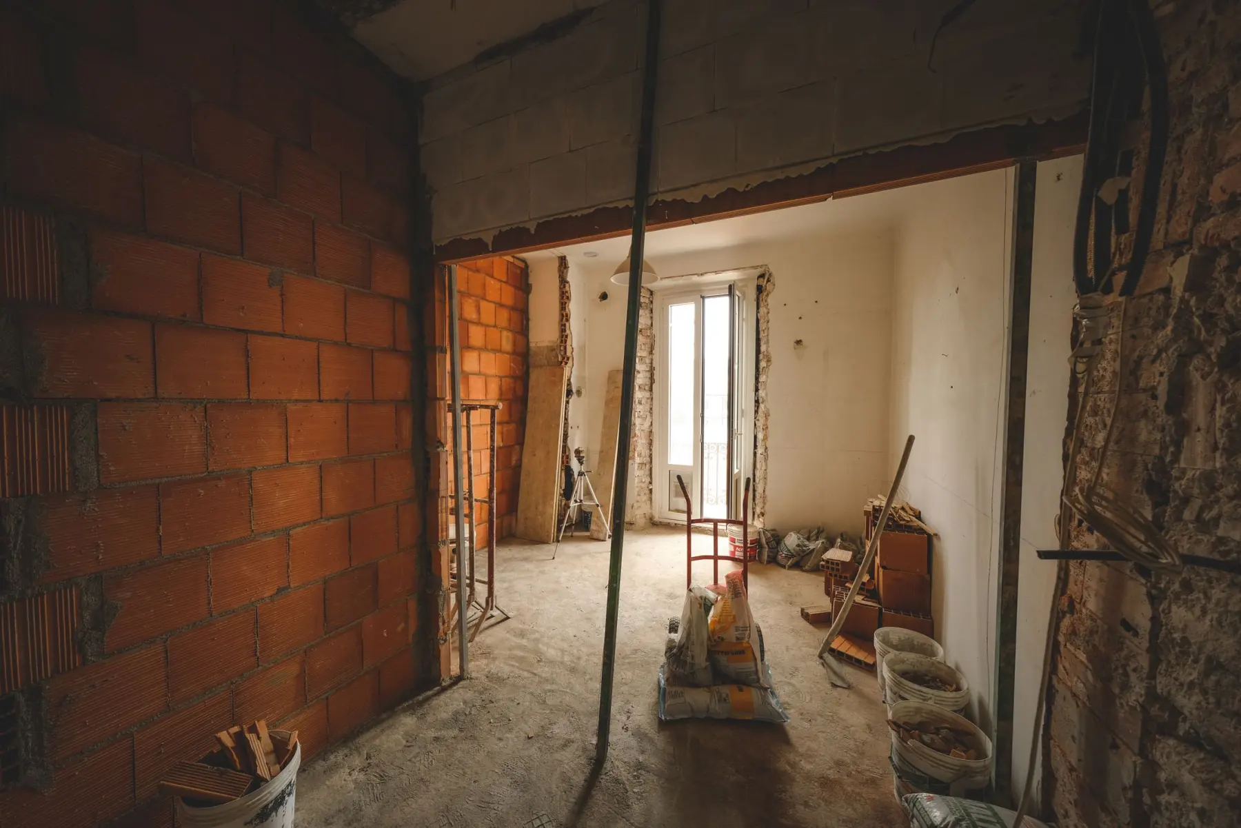 Pièce en cours de rénovation : murs en brique mis à nu et matériaux de chantier
